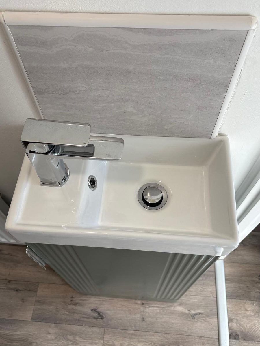A compact basin with a waterfall tap above a painted vanity